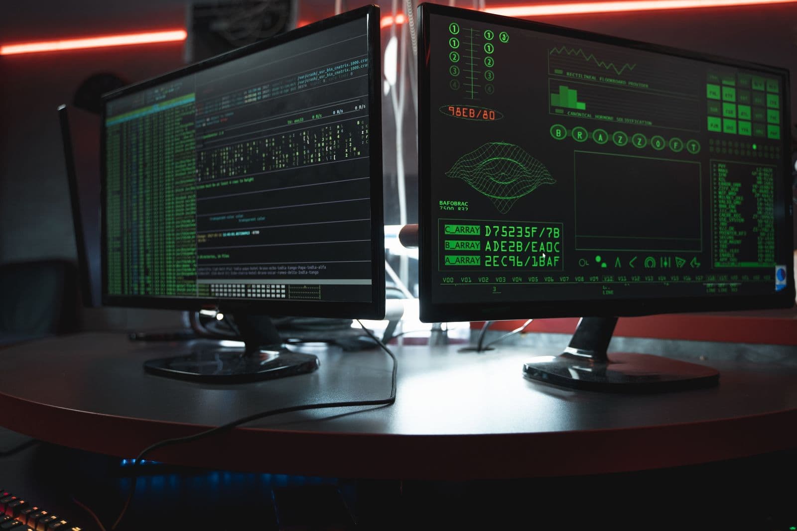 Two monitors showing terminal output in a dark room