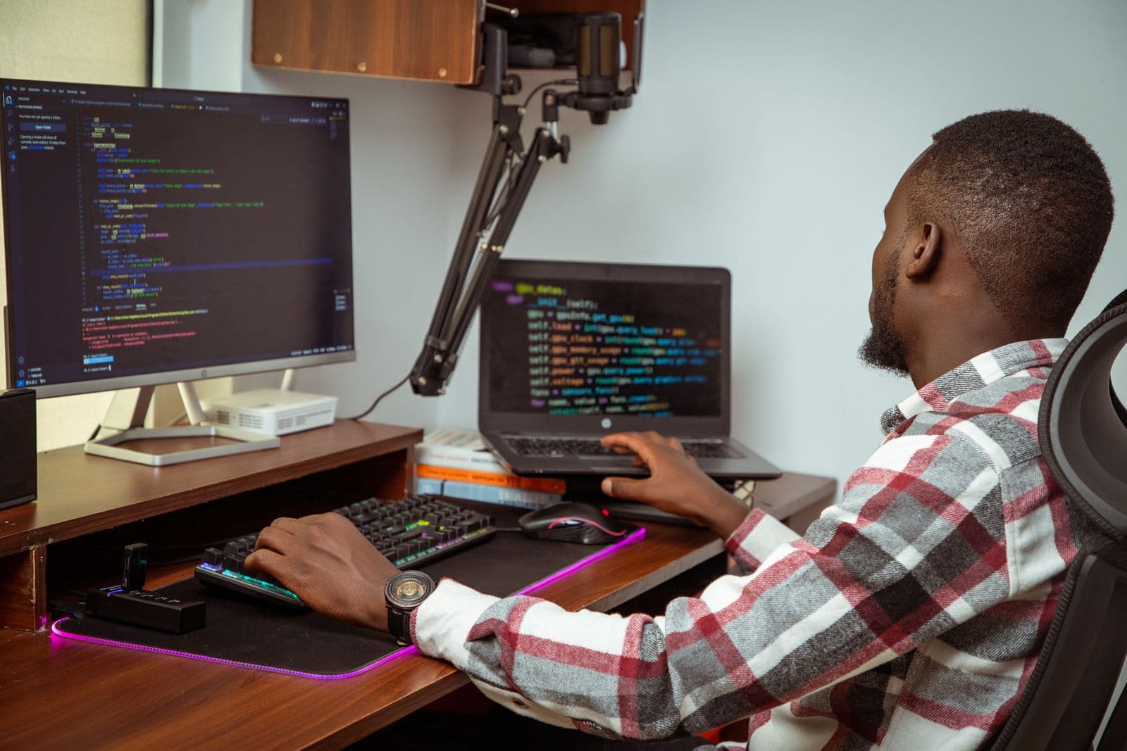 A developer writing code on a laptop and an external monitor
