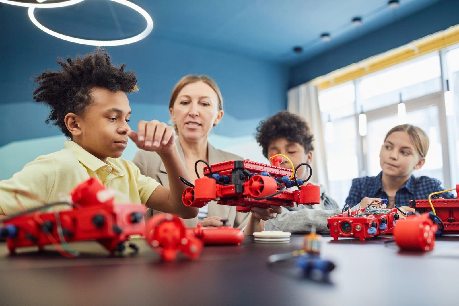 Children and a teacher assembling a robot kit together